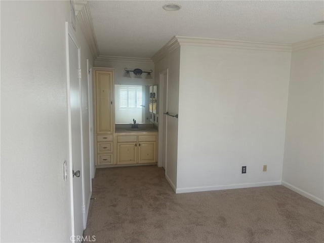 hallway with a sink, baseboards, light colored carpet, and crown molding