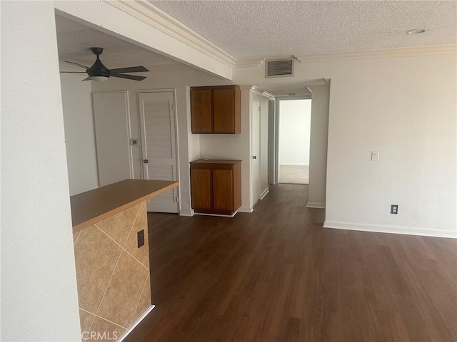 interior space with visible vents, ornamental molding, a textured ceiling, and dark wood-style flooring