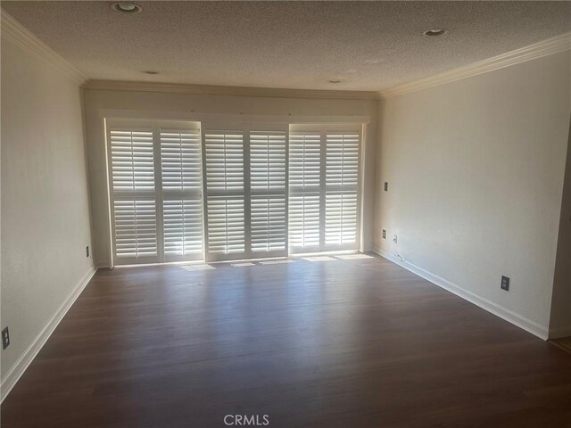 empty room with a textured ceiling, wood finished floors, baseboards, and ornamental molding