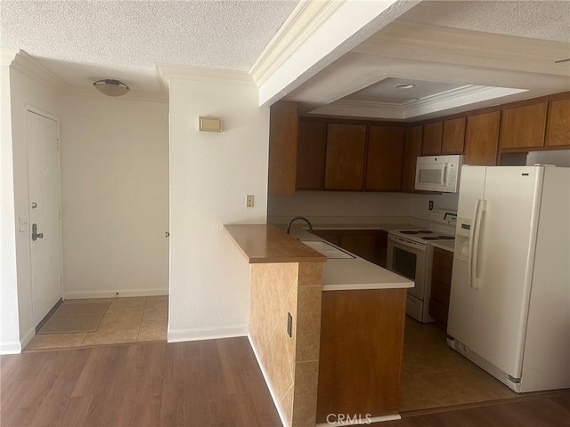 kitchen with white appliances, a peninsula, a sink, a textured ceiling, and crown molding