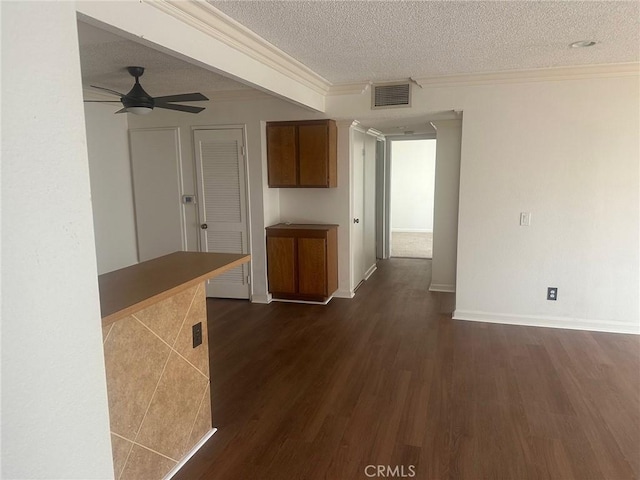 interior space with ornamental molding, visible vents, dark wood-style flooring, and a textured ceiling