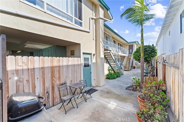 view of patio featuring a grill, fence private yard, and stairs