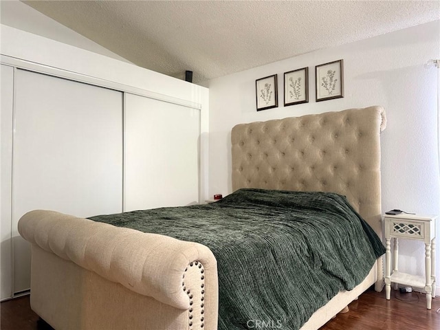 bedroom with lofted ceiling, wood finished floors, a closet, and a textured ceiling