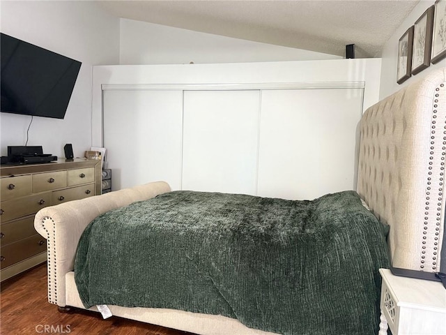 bedroom featuring a closet, lofted ceiling, and dark wood finished floors