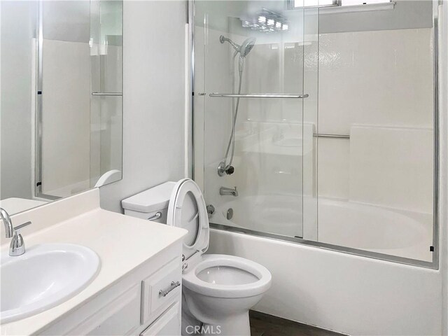 bathroom with toilet, vanity, and shower / bath combination with glass door