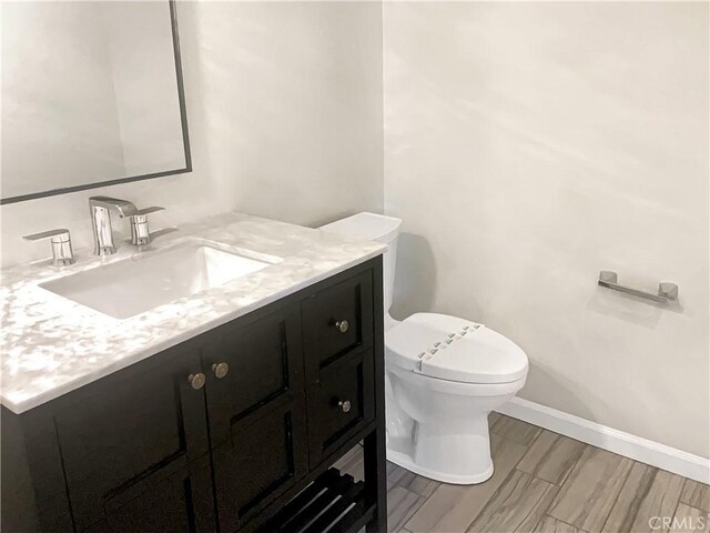 bathroom featuring baseboards, toilet, and vanity