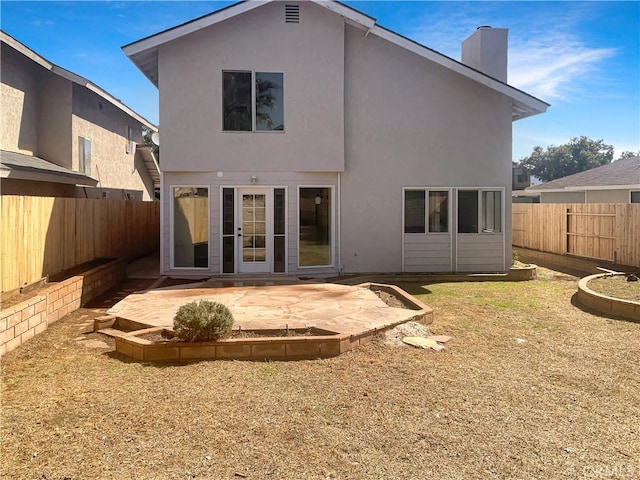 back of house featuring a patio area, a fenced backyard, a chimney, and stucco siding