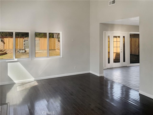 unfurnished room featuring visible vents, baseboards, and dark wood-style floors