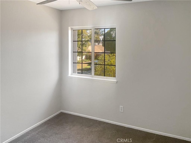 unfurnished room featuring baseboards and dark colored carpet