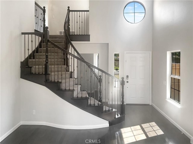 foyer featuring plenty of natural light, baseboards, and a towering ceiling