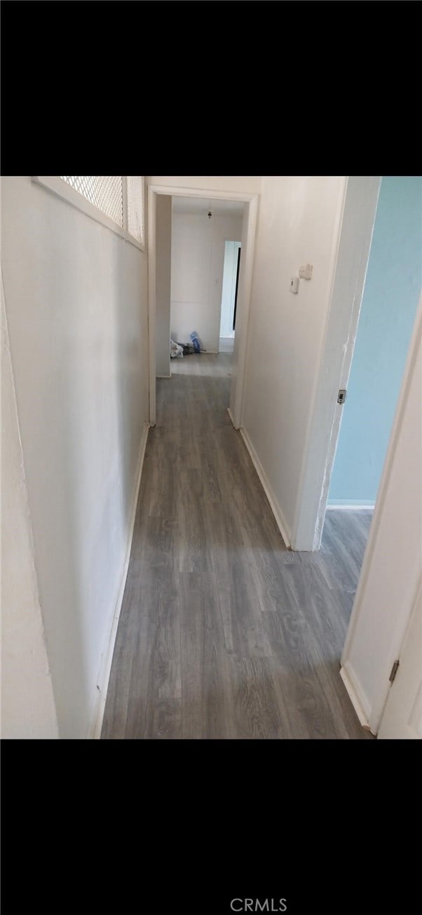 hallway featuring baseboards and wood finished floors