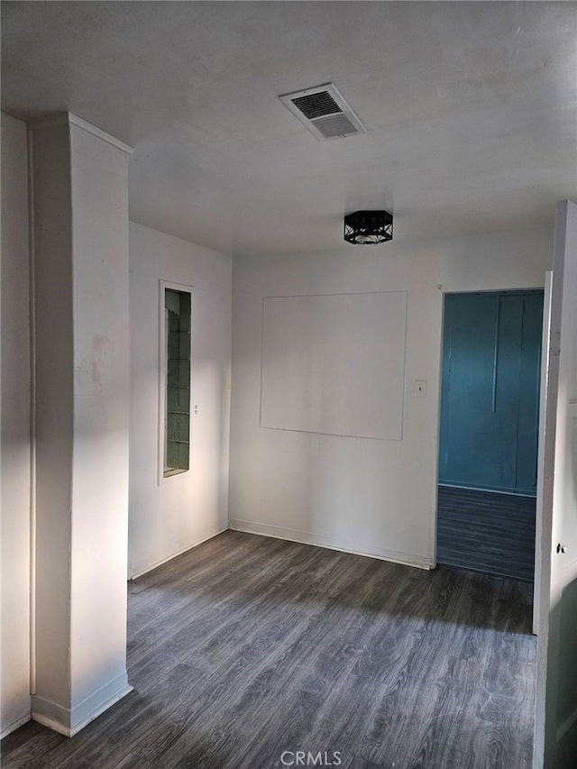 unfurnished room with visible vents, baseboards, and dark wood finished floors