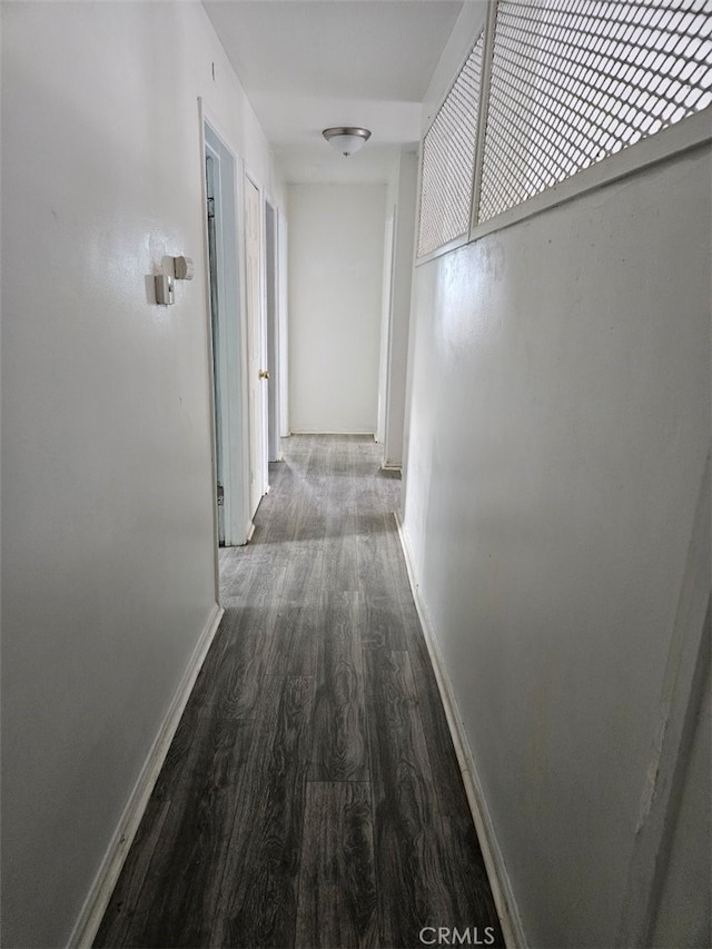 hallway featuring wood finished floors and baseboards