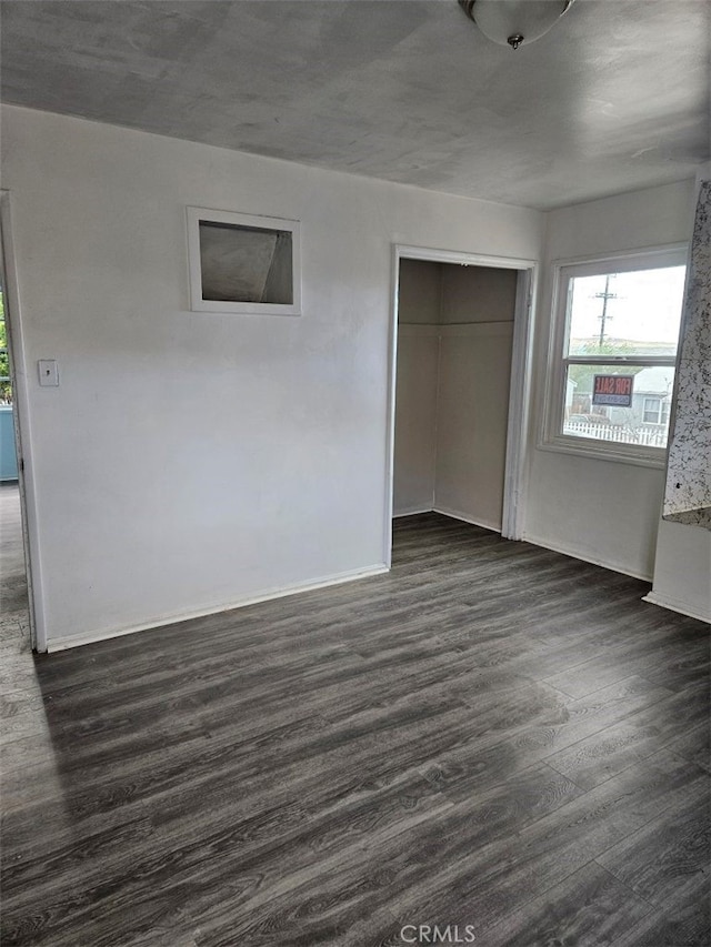 unfurnished bedroom with baseboards, dark wood-style flooring, and a closet