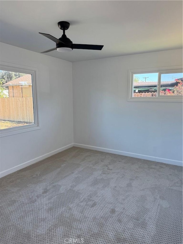 carpeted spare room featuring a ceiling fan and baseboards