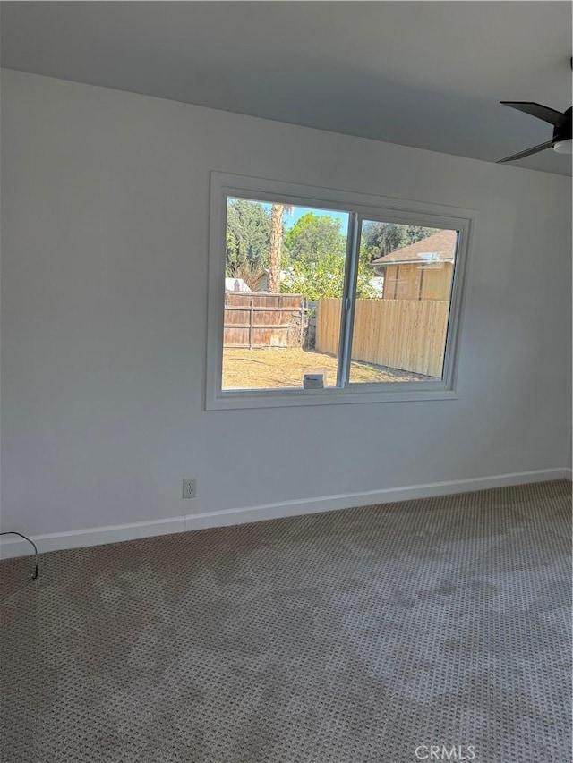 carpeted empty room featuring baseboards and a ceiling fan