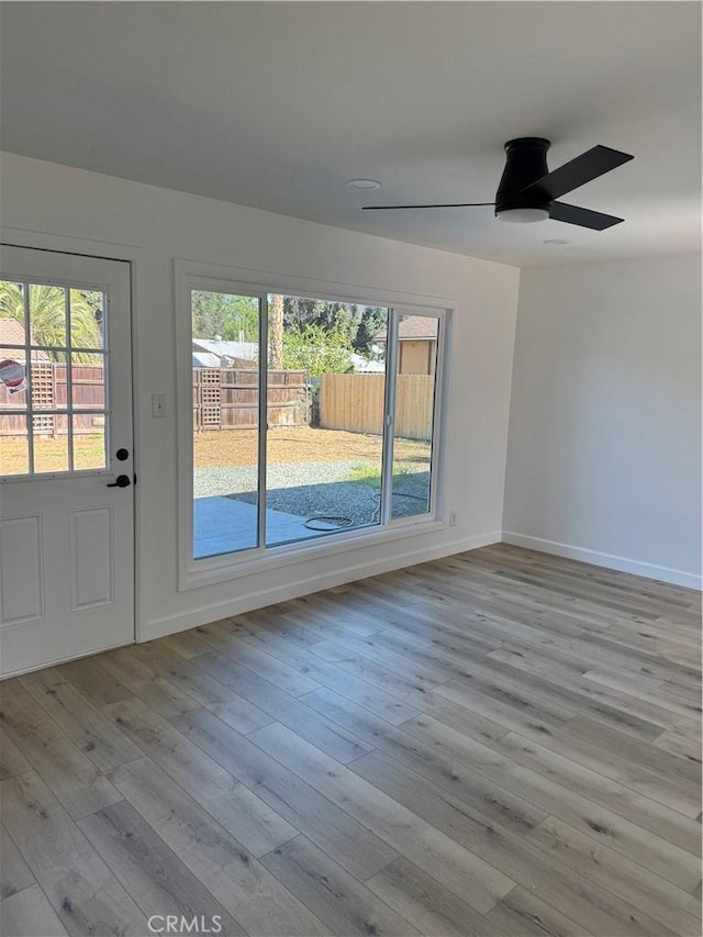 empty room featuring ceiling fan, baseboards, and wood finished floors