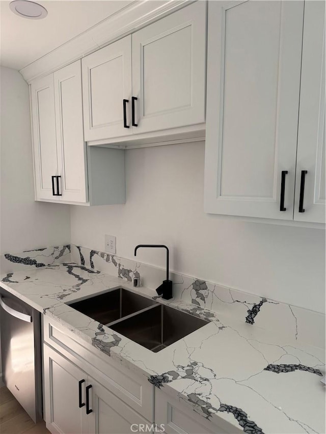 kitchen featuring a sink, light stone counters, dishwasher, and white cabinets