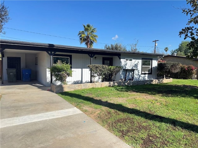 ranch-style home with a front lawn, a carport, and driveway