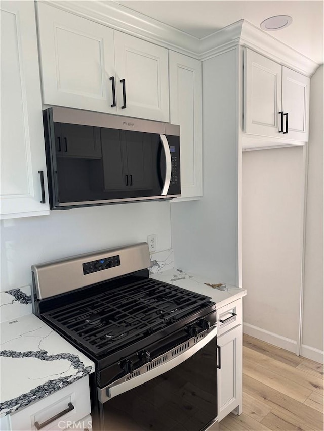 kitchen featuring light stone countertops, baseboards, stainless steel appliances, white cabinets, and light wood-type flooring