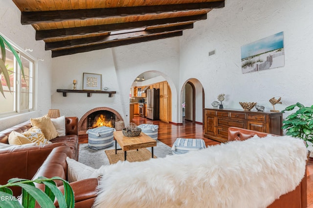 5451 Reef Way, Oxnard, CA 93035 - living room with arched walkways, a textured wall, wood finished floors, a lit fireplace, and a wooden ceiling with exposed beams
