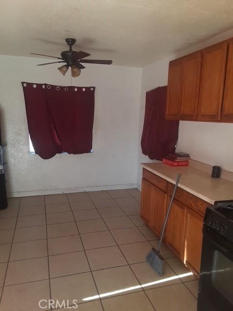 kitchen featuring black gas stove, light countertops, a ceiling fan, and brown cabinets