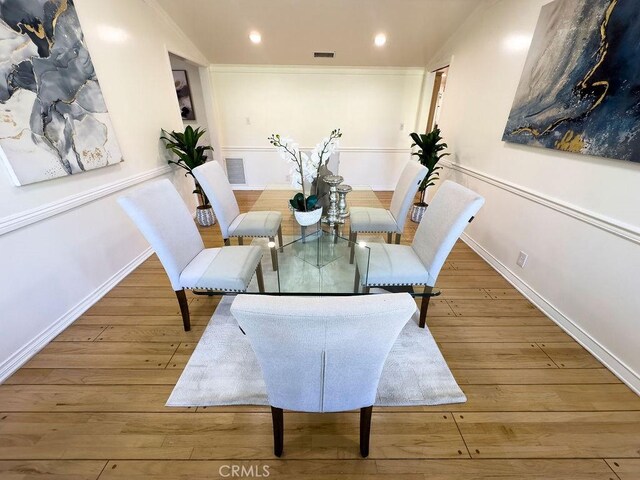 dining area with hardwood / wood-style floors, recessed lighting, visible vents, and ornamental molding