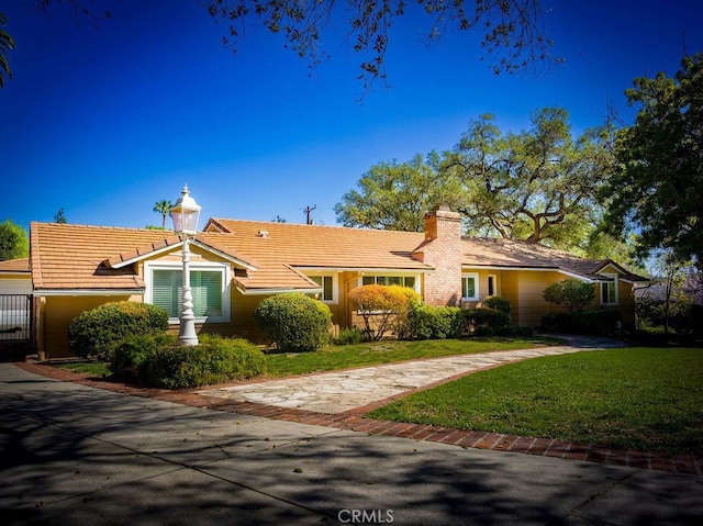 single story home with a tiled roof, a chimney, and a front yard