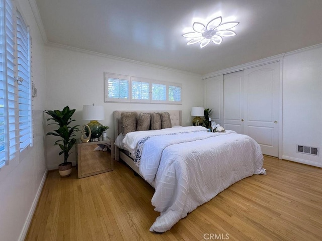 bedroom featuring visible vents, baseboards, ornamental molding, and light wood finished floors