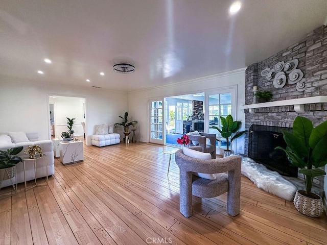 living room with recessed lighting, a brick fireplace, hardwood / wood-style floors, and crown molding