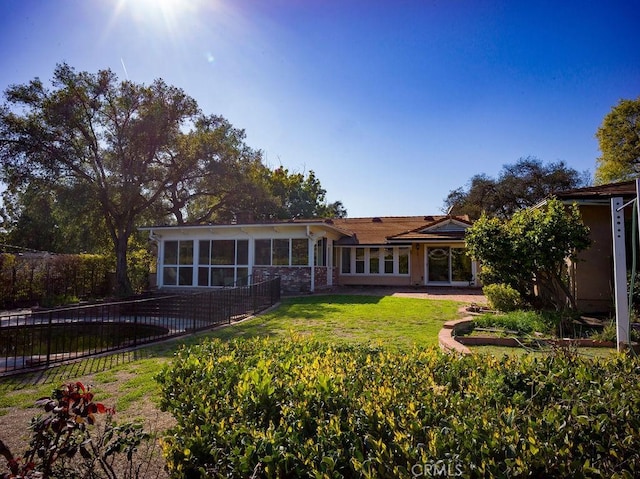 back of house featuring a patio area, a lawn, fence, and a sunroom