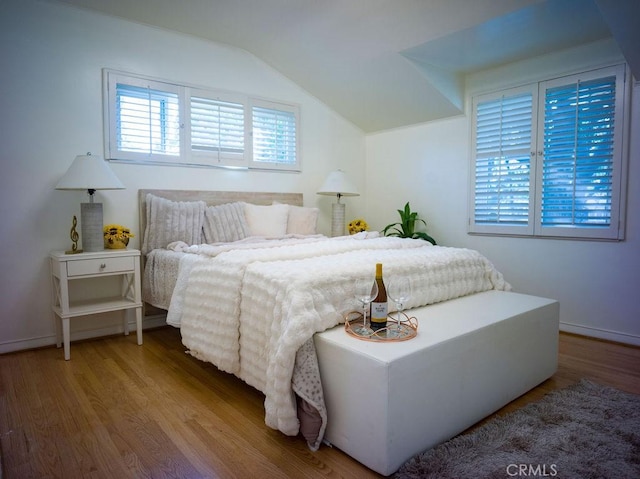 bedroom featuring baseboards, lofted ceiling, and wood finished floors