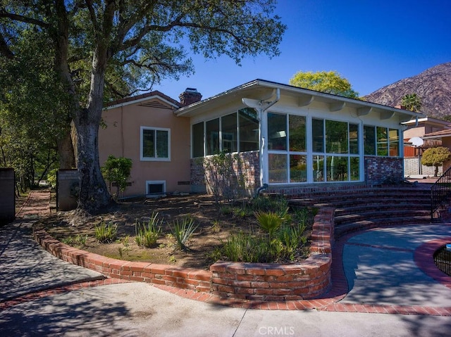 exterior space with stucco siding, a chimney, and a sunroom