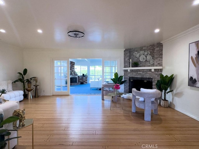 living room with ornamental molding, a brick fireplace, and wood-type flooring