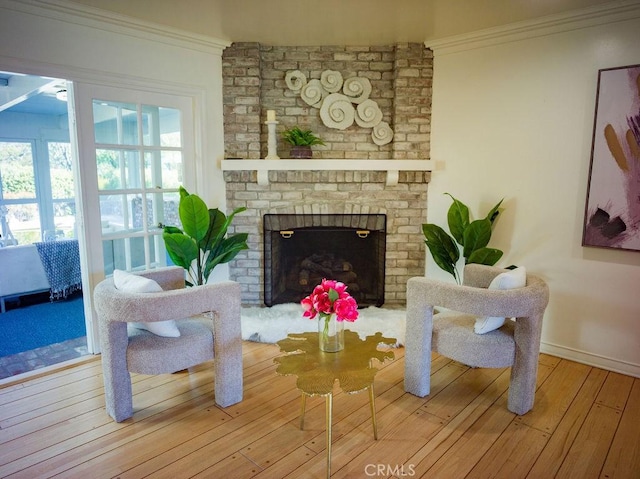 living room featuring baseboards, wood-type flooring, ornamental molding, and a fireplace