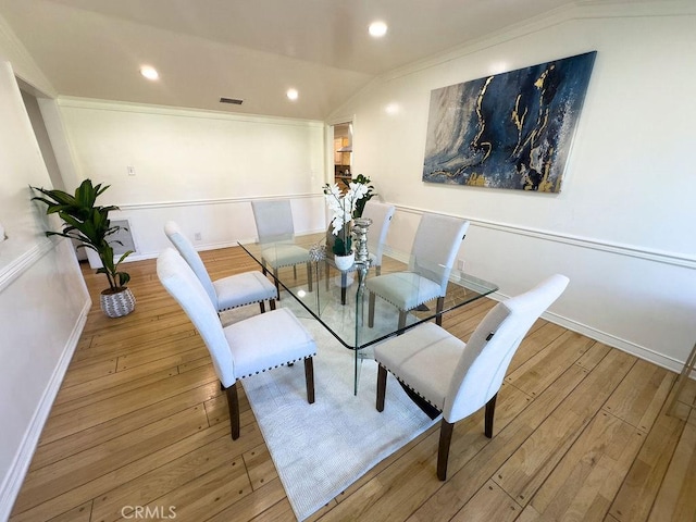 dining room featuring hardwood / wood-style floors, vaulted ceiling, recessed lighting, and visible vents