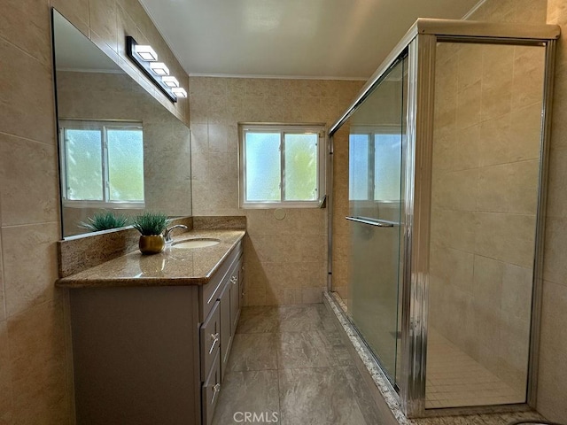 bathroom with vanity, tile walls, ornamental molding, and a shower stall