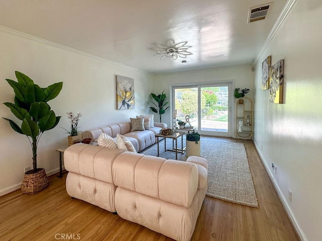 living area with visible vents, a ceiling fan, wood finished floors, crown molding, and baseboards