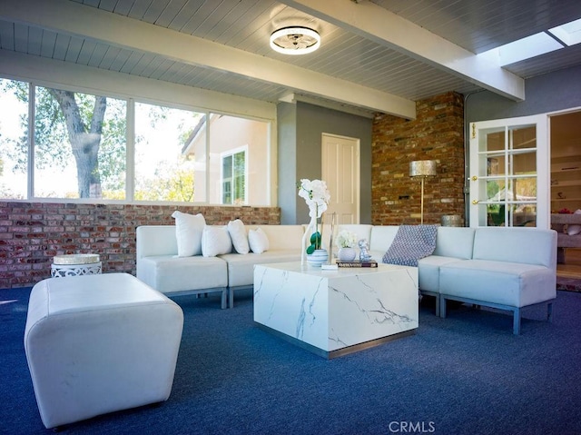 interior space featuring beam ceiling, brick wall, and a wealth of natural light