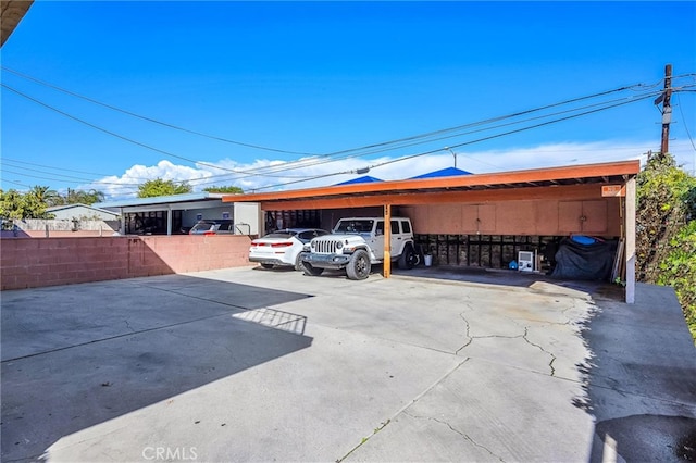 view of parking with a carport and fence