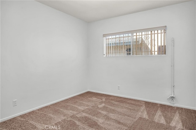 carpeted empty room featuring baseboards