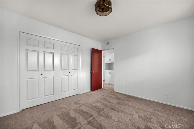 unfurnished bedroom with a closet, carpet flooring, visible vents, and baseboards