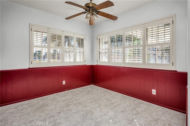 spare room featuring a wealth of natural light and wainscoting