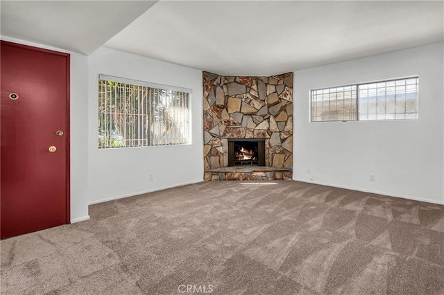 unfurnished living room with carpet floors and a stone fireplace