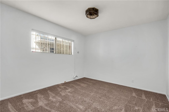 empty room featuring carpet and baseboards