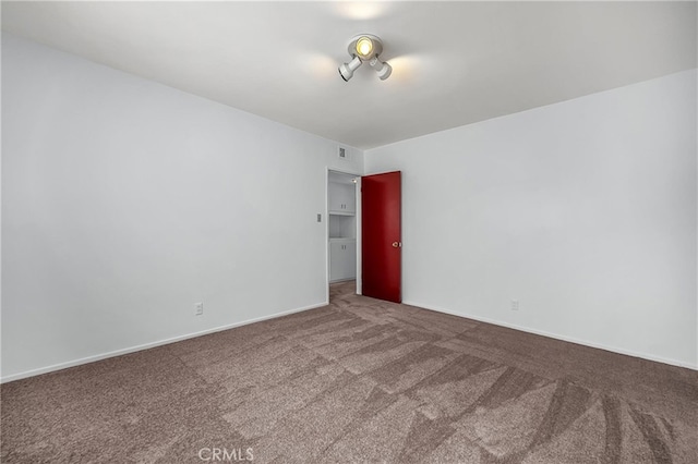 empty room with carpet, visible vents, and baseboards