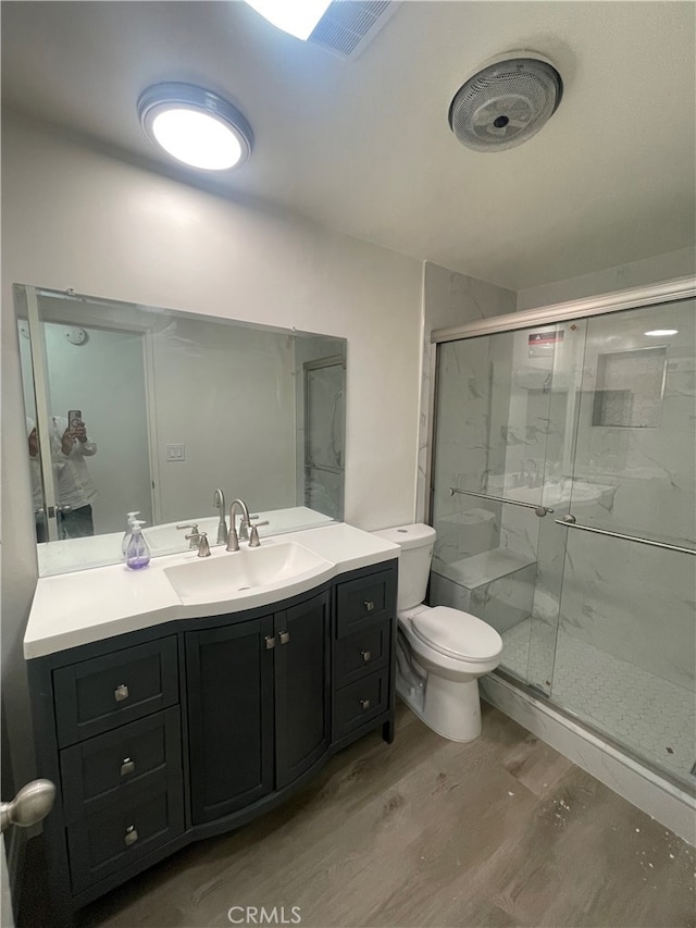 full bathroom featuring vanity, wood finished floors, visible vents, a shower stall, and toilet