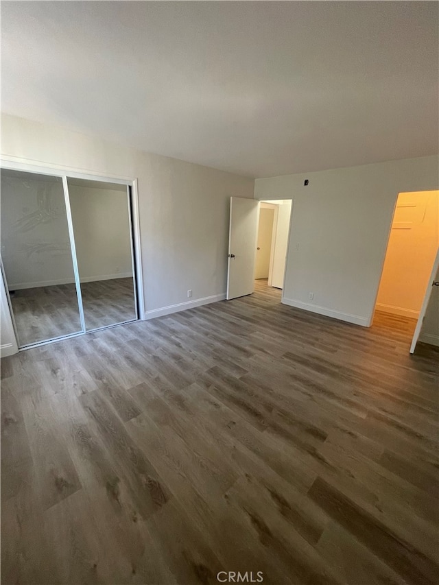 unfurnished bedroom with a closet, baseboards, and wood finished floors