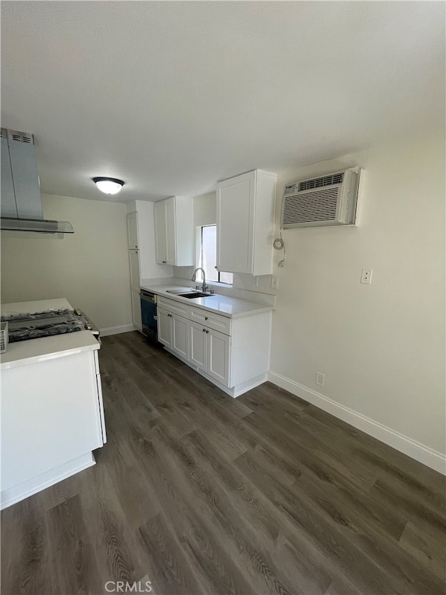 kitchen featuring wall chimney range hood, a wall unit AC, dark wood-style flooring, white cabinetry, and a sink