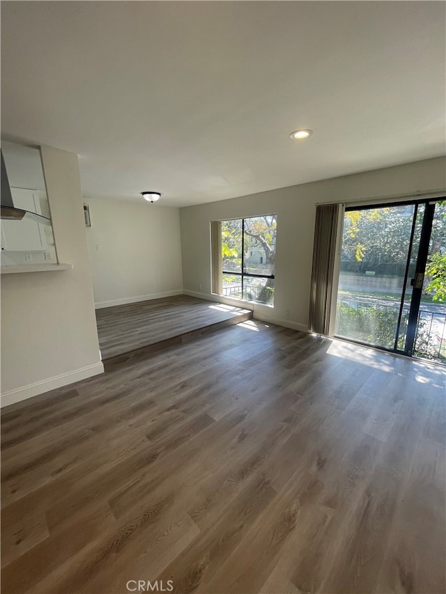 unfurnished living room featuring recessed lighting, wood finished floors, and baseboards